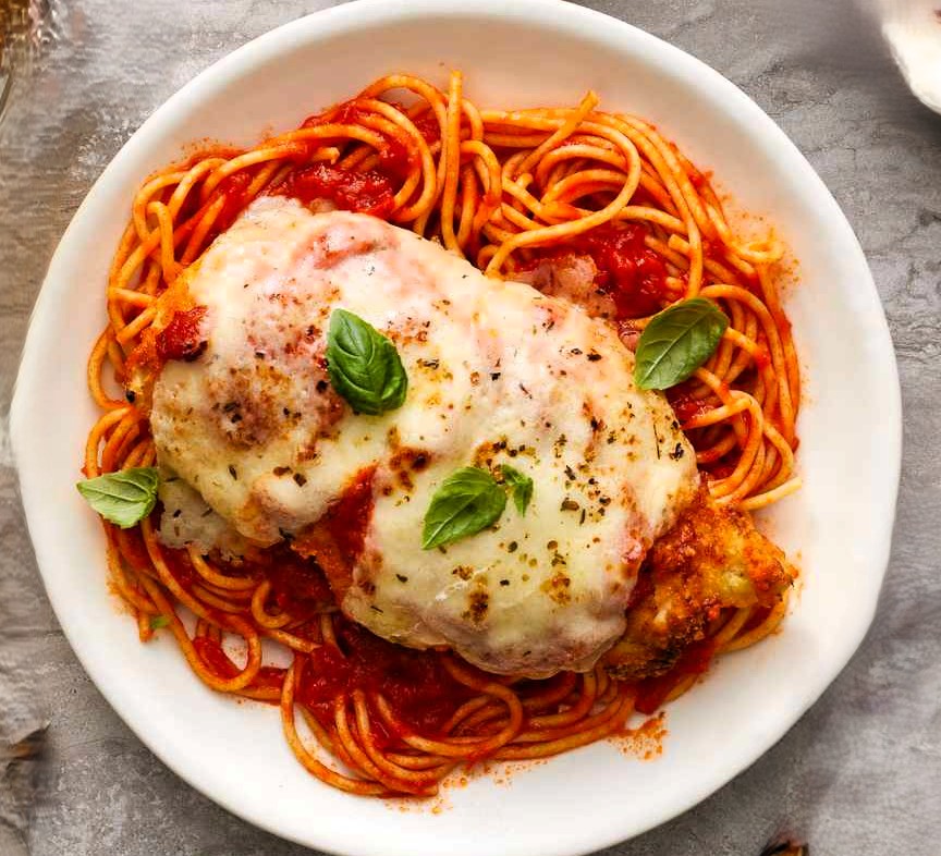 Chicken parmesan over spaghetti with marinara and basil