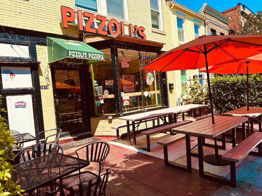 Pizzolis Pizzeria storefront with green awning and patio seating