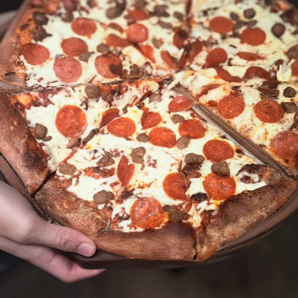 Deep-dish meat lovers pizza being served